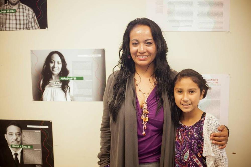 Woman and child standing in front of a portrait of the woman